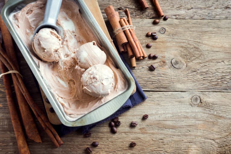 Homemade ice cream with scoop in frozen metallic container on wooden background with copy space