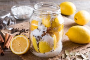 Preserved lemons with salt on a wooden board with lemon juice and spices