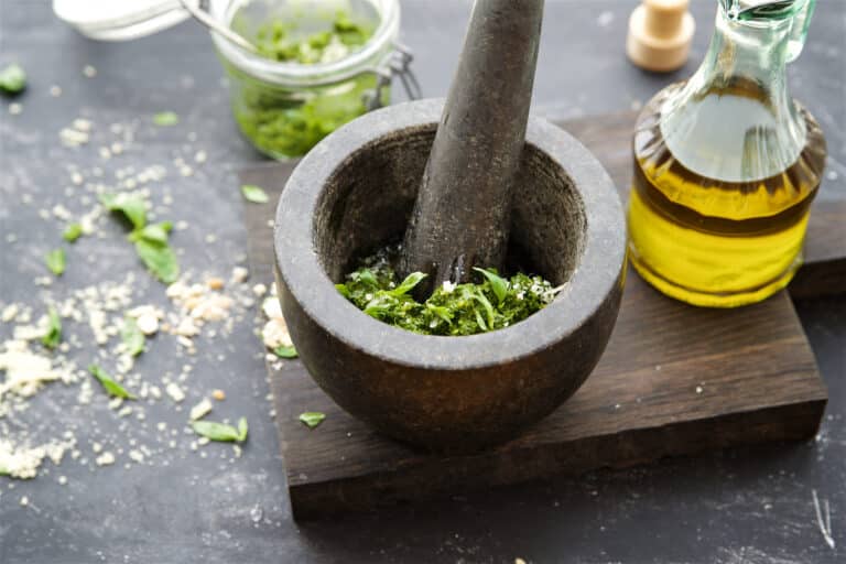 Basil pesto in a mortar on a wooden background