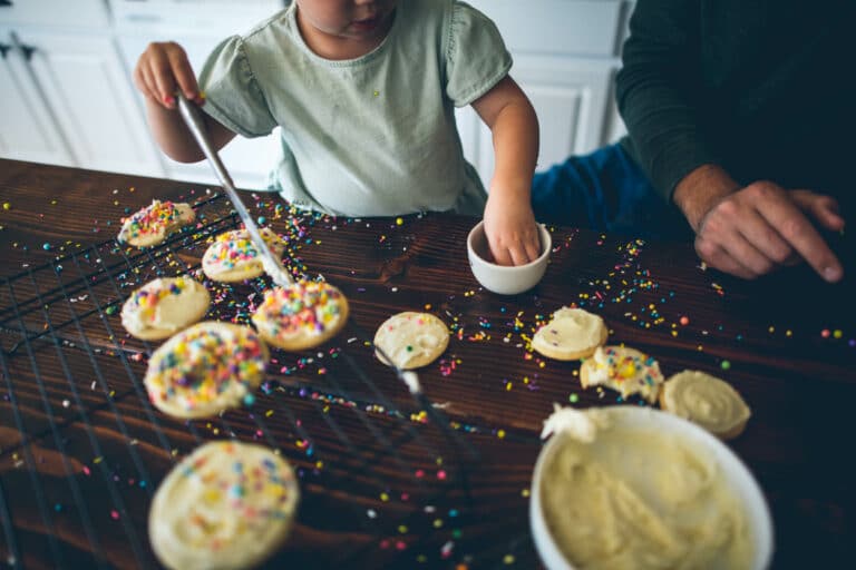 cropped image of a child decorating sugar cookies