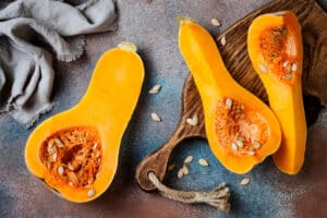 Butternut squash on wooden board over rustic background. Healthy fall cooking concept