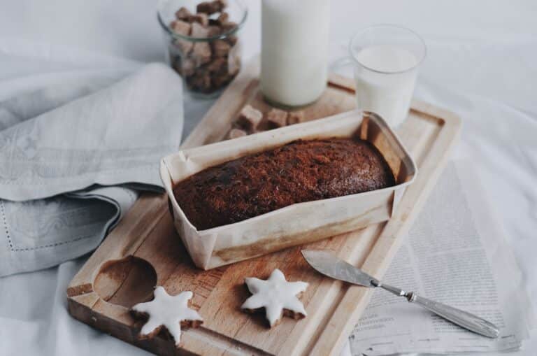 gingerbread loaf on a cutting board with a glass of milk and two star cookies