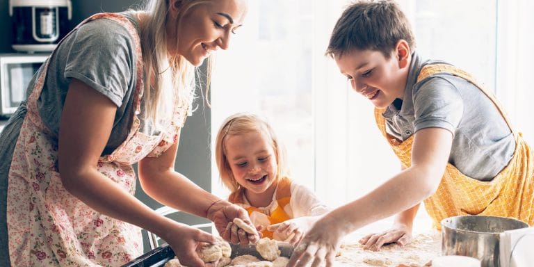 a mom and two kids making biscuits on a floured countertop