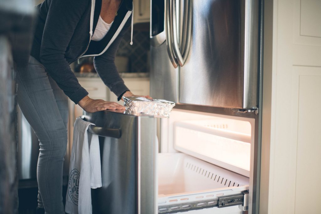 cropped image of a woman putting leftovers in the freezer