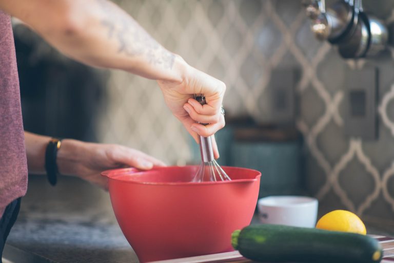 A person mixing something with a whisk in a red bowl
