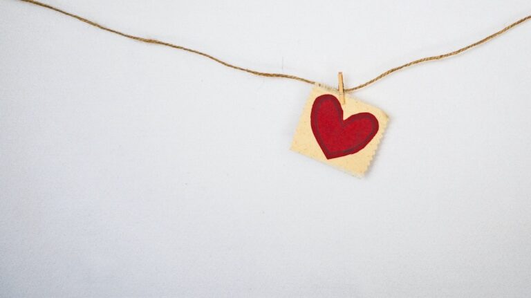 A red paper heart on a string with a white background