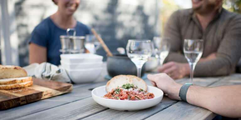 cropped image of people sitting around a table of food and wine glasses