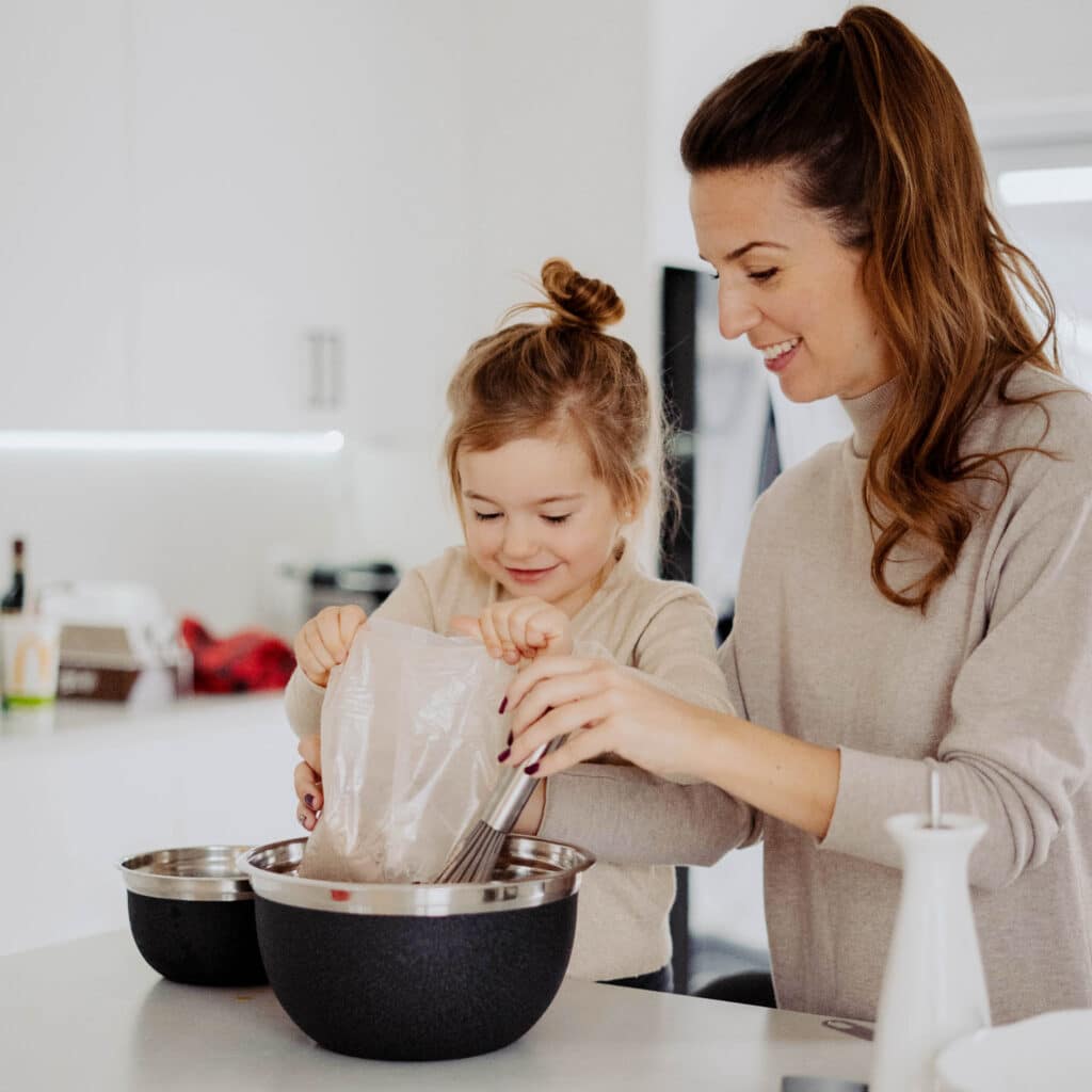 Young mom and daughter making cupcakes in a white kitchen