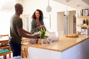 Couple Returning Home From Shopping Trip Unpacking Plastic Free Grocery Bags