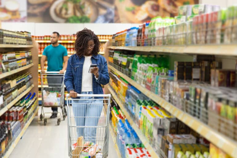 Front view of woman reading shopping list on smartphone. Serious woman with dreadlocks looking at smartphone. Shopping concept