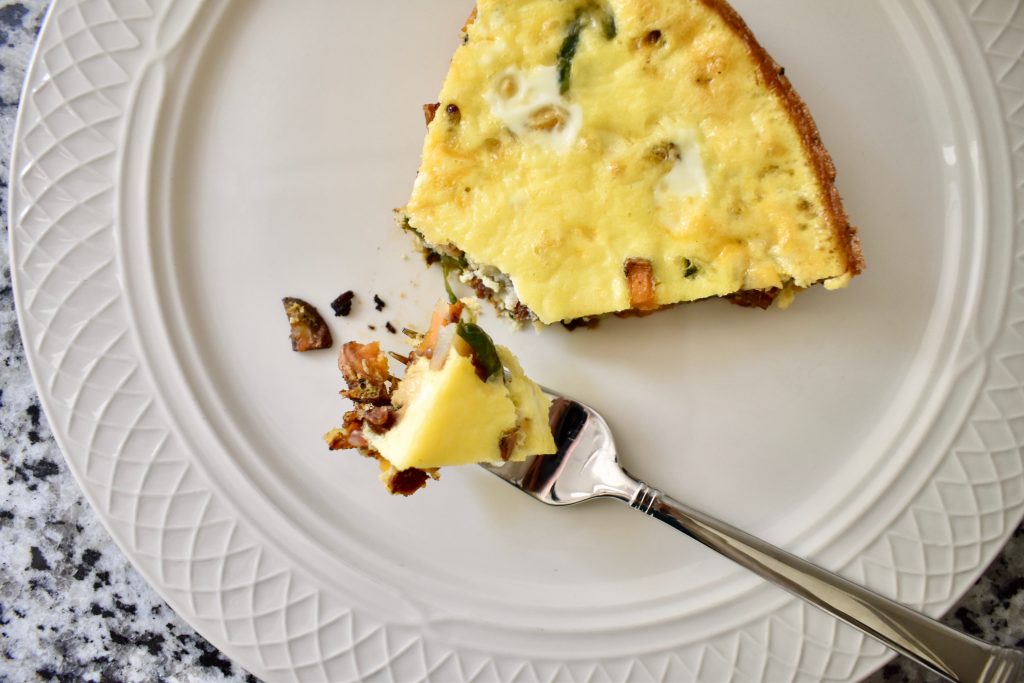 bite of frittata on a fork on a white circular plate