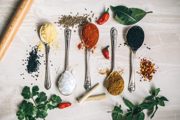 Overhead shot of colorful spices on spoons in a row laying on a table
