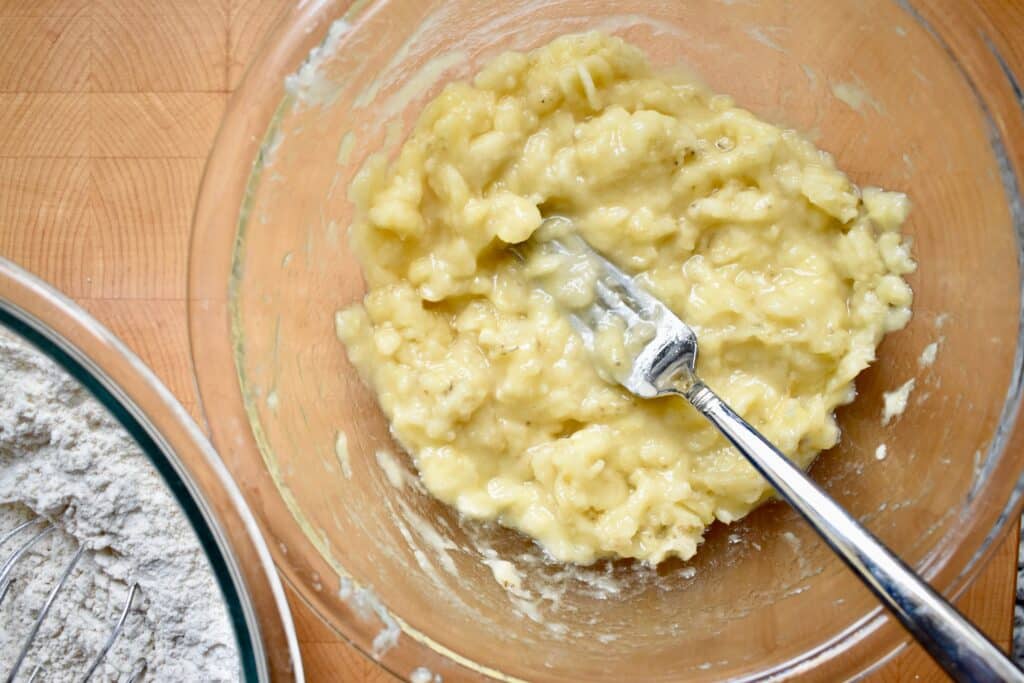 overhead shot of mashed bananas in a glass bowl