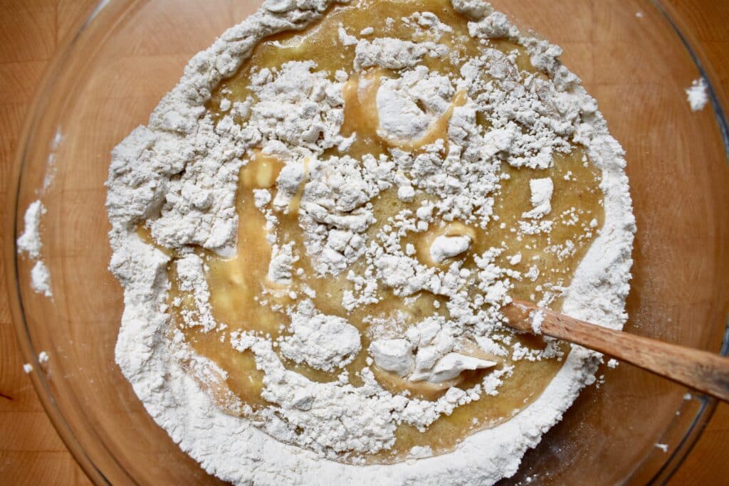 overhead shot of flour being mixed into the wet ingredients for banana bread