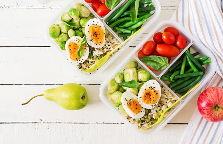 Vegetarian meal prep containers with eggs, brussel sprouts, green beans and tomato. Dinner in lunch box. Top view. Flat lay