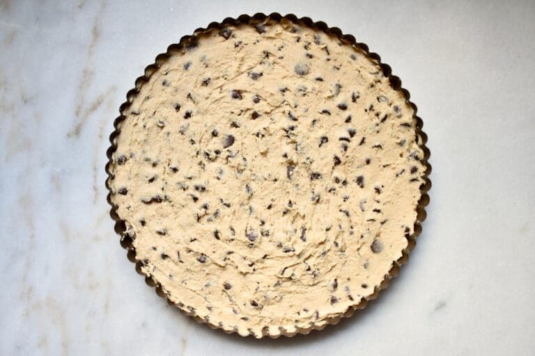 overhead shot of cookie dough spread into the tart pan