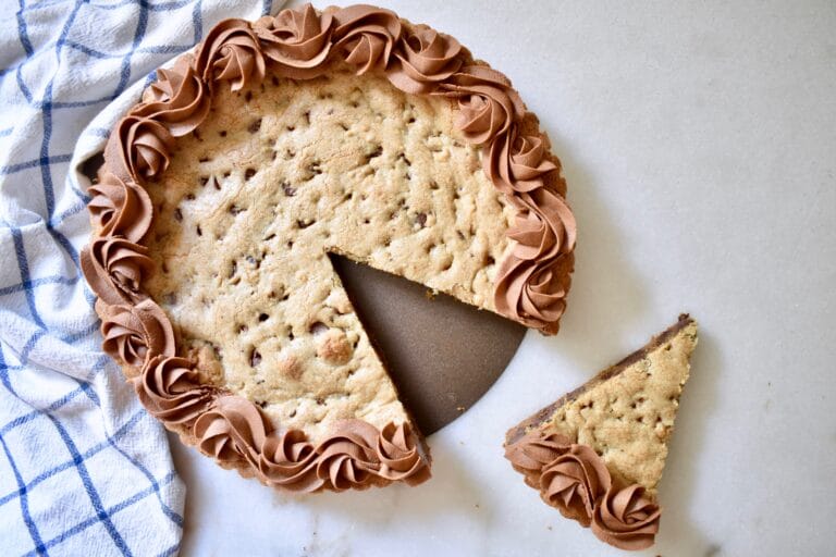 overhead shot of decorated chocolate chip cookie cake with a slice cut out of it