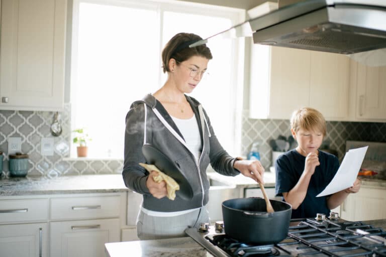 Young white woman and son cook from a recipe in a bright kitchen