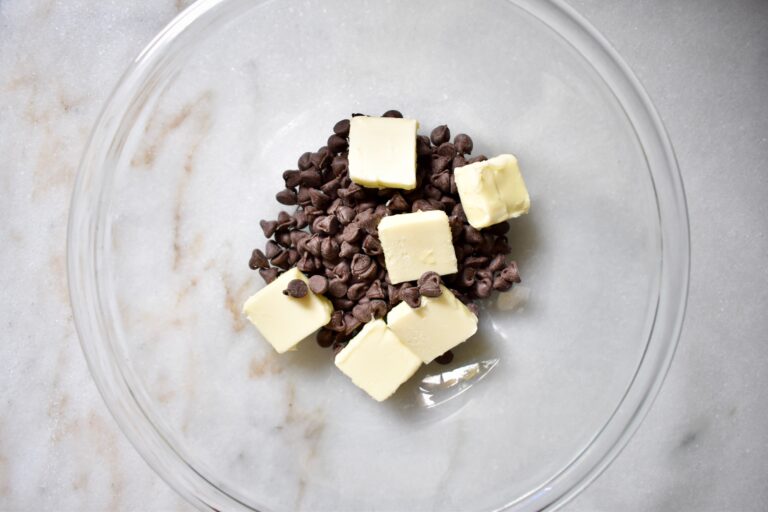 overhead shot of chocolate chips and butter in a glass bowl
