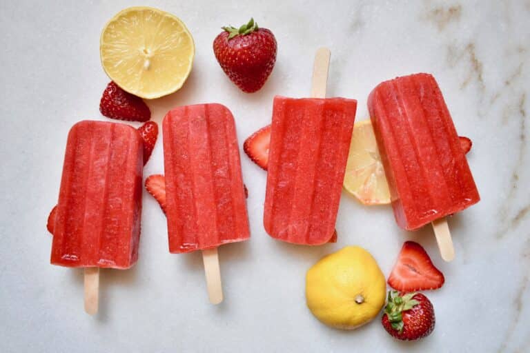 overhead shot of strawberry popsicles with lemons and strawberries around them