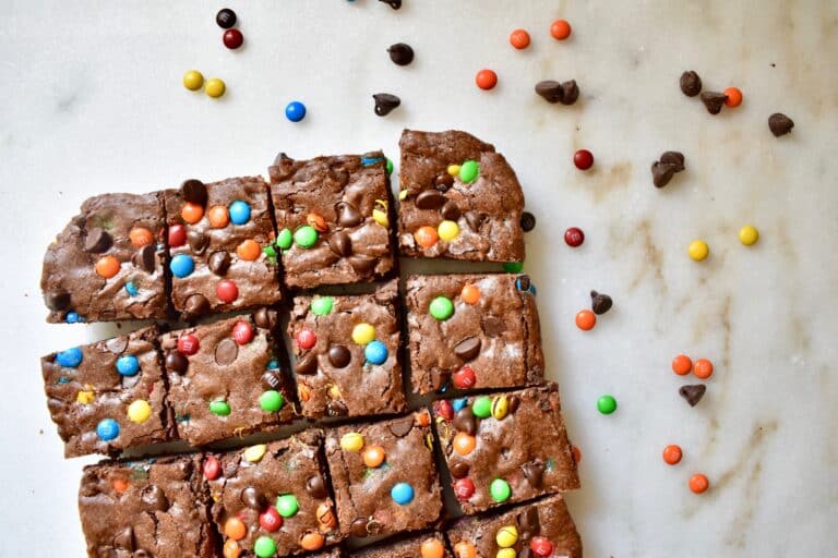 cropped overhead shot of baked brownies, cut into squares with m&ms scattered around