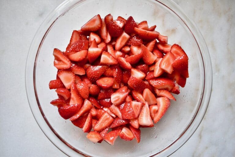 overhead shot of cut strawberries in a glass bowl