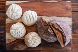 overhead image of a loaf of dark bread and four sweet rolls