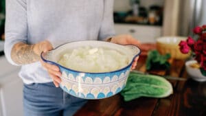 cropped image of woman holding blue and white ceramic pot filled with mashed potatoes