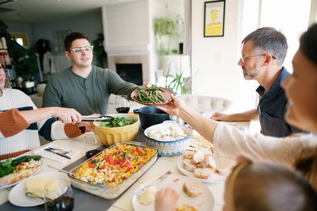 image of people around a dinner table, passing food to each other