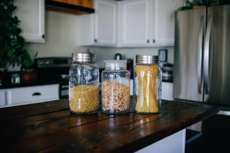 three glass containers of noodles on a kitchen counter