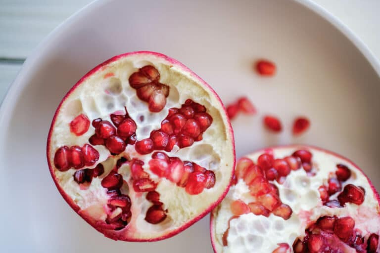 overhead shot of a pomegranate cut in half on a white plate