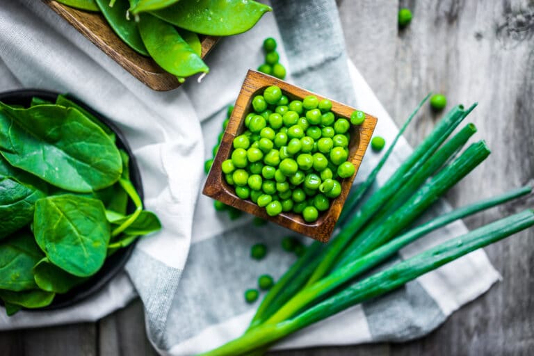 Spring vegetables, peas, green onions, and spinach, on wooden background