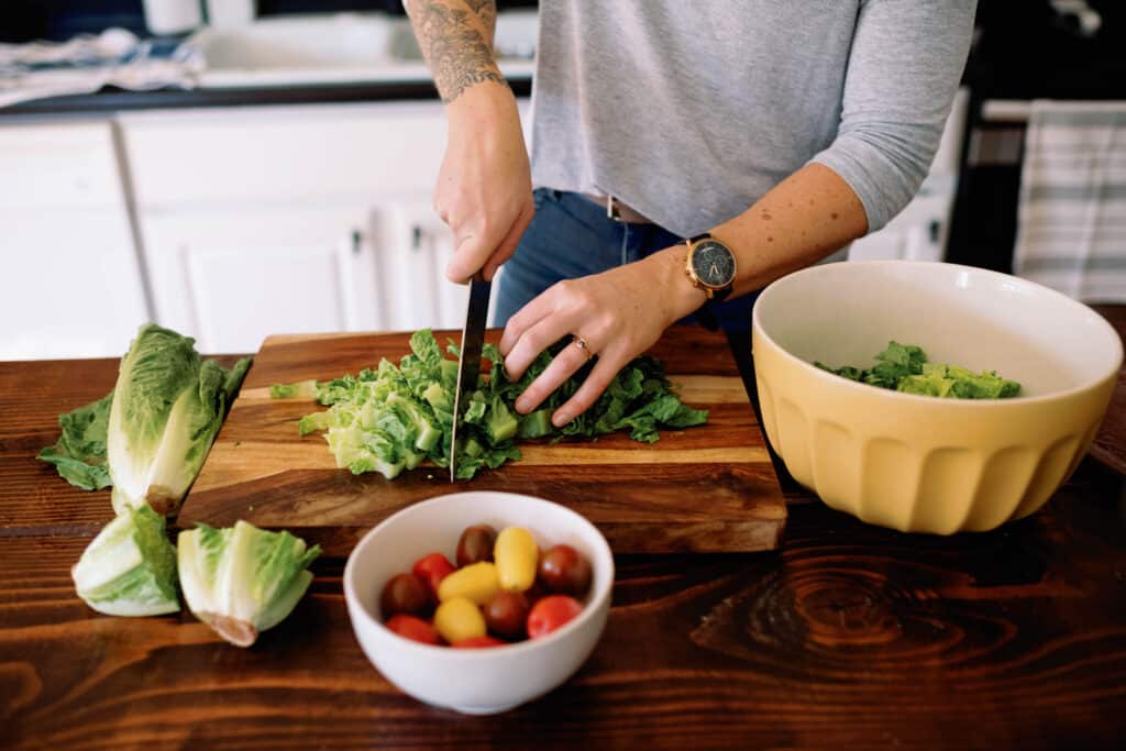 cropped image of white woman chopping lettuce for a salad