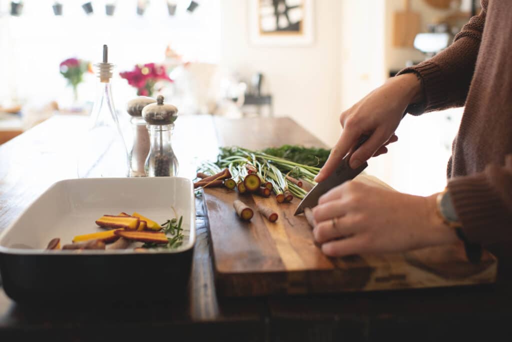 side view of a woman cutting carrots in a bright kitchen