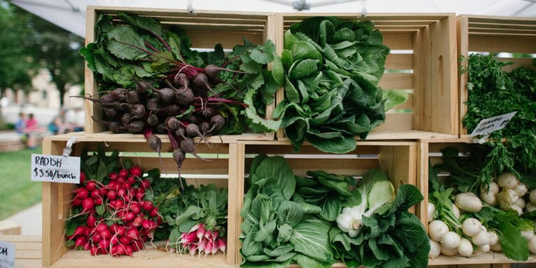 wooden boxes holding fresh lettuce and radishes at a farmer's market display