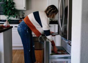 woman getting food out of freezer with cell phone in her hand