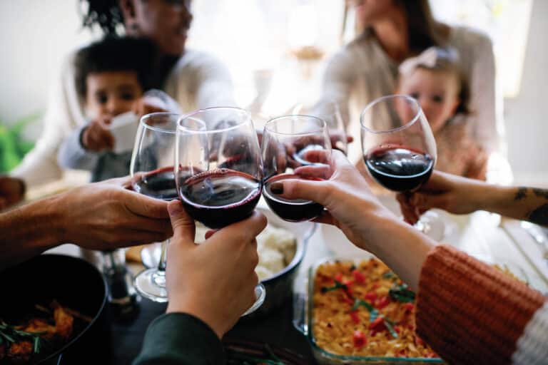 side view of people cheersing glasses of red wine