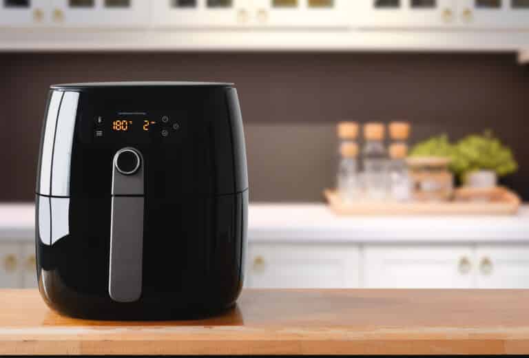 A black air fryer sitting on a kitchen counter.