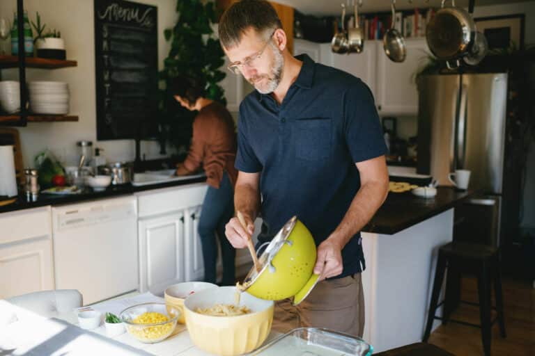 Man preparing recipe at kitchen table with yellow bowls of ingredients.