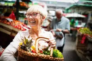older woman holding a basket of produce at a market