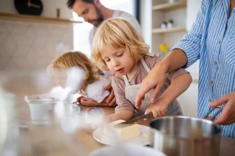 close up of young child helping to cut butter in the kitchen