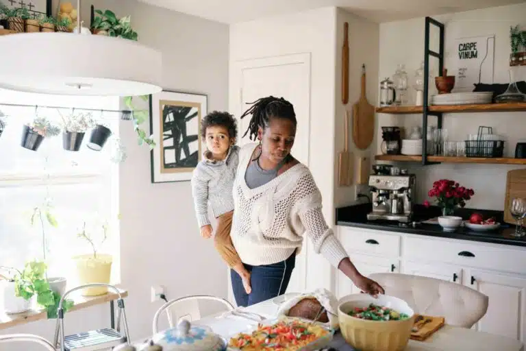 image of woman setting the table in a bright room with a child on her hip