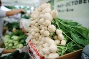 close up on a bunch of white radishes at a farmer's market stand
