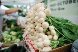 close up on a bunch of white radishes at a farmer's market stand