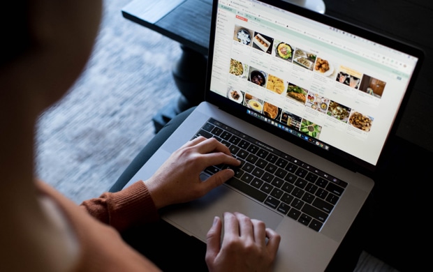 overhead shot of a woman working at her computer with a digital recipe book on the screen