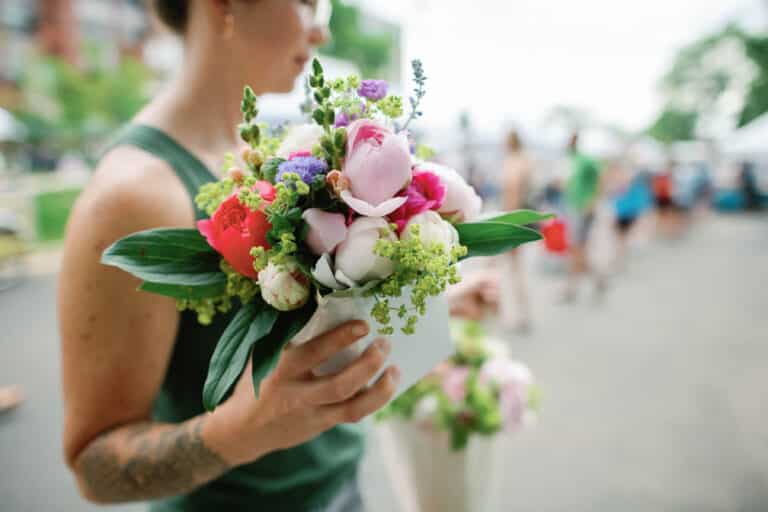 image of woman holding a bouquet of flowers at a farmer's market