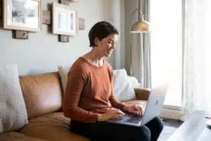 woman sitting on a couch with a computer on her lab, smiling