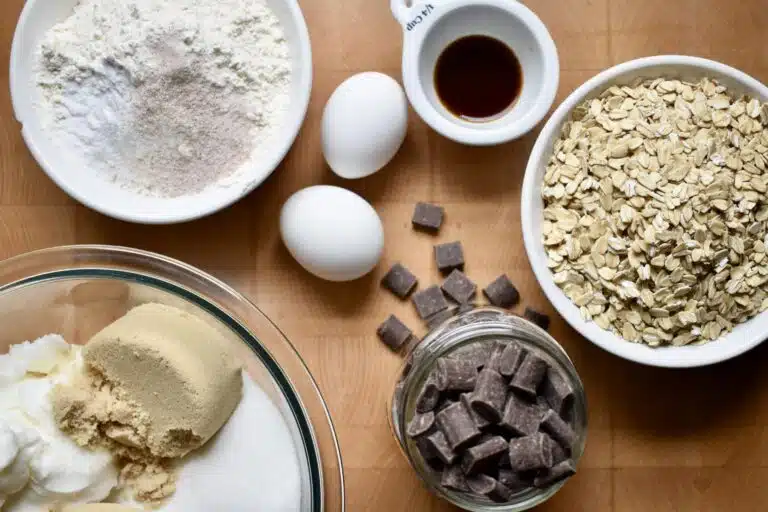 overhead image of chocolate chunk oatmeal cookie ingredients, flour, vanilla, brown sugar, chocolate chunks, dry oatmeal