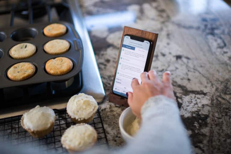 phone on stand with recipe instruction with cupcakes in the background