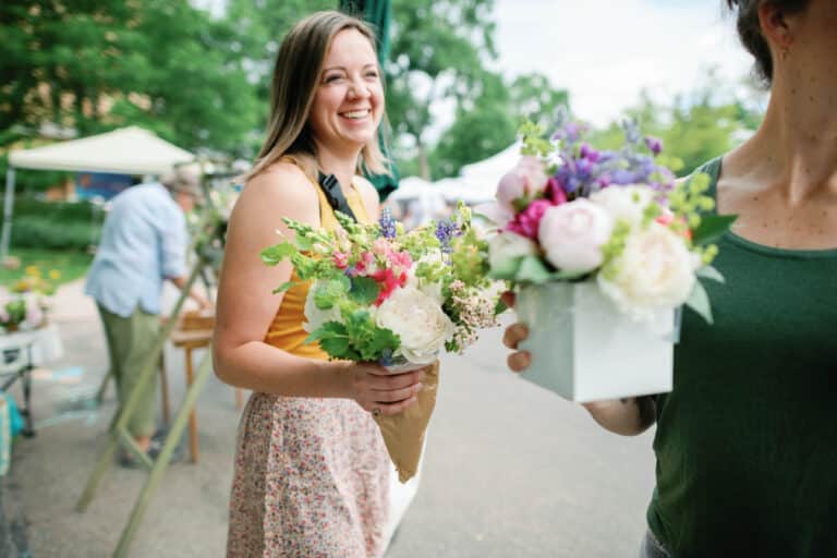 a woman laughing while holding a bouquet of flowers